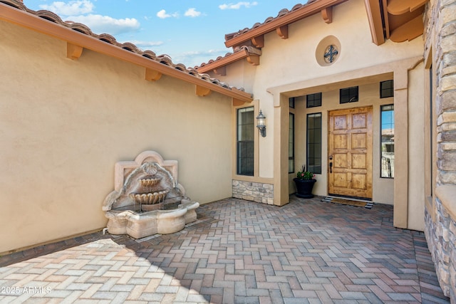 view of exterior entry featuring stone siding and stucco siding