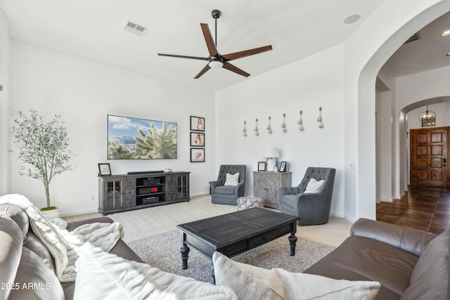 living room featuring arched walkways, ceiling fan, visible vents, and baseboards