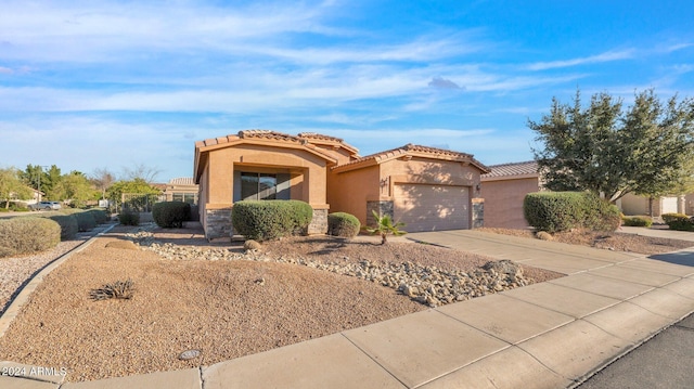 mediterranean / spanish house featuring stone siding, driveway, an attached garage, and stucco siding