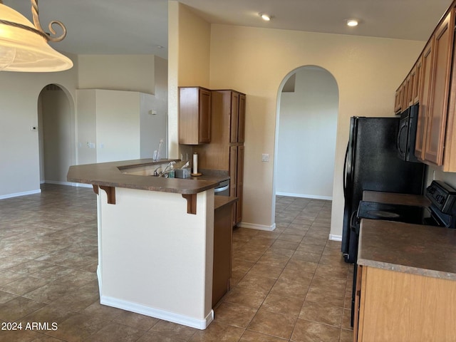 kitchen featuring kitchen peninsula, dark tile patterned floors, and a breakfast bar area