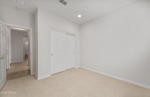 unfurnished bedroom featuring light carpet and a closet