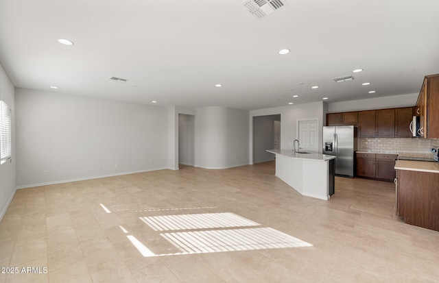 kitchen featuring backsplash, sink, stainless steel appliances, and an island with sink