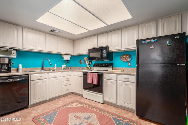 kitchen with white cabinets, light tile patterned floors, sink, and black appliances