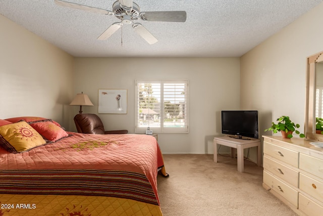 bedroom featuring ceiling fan, light colored carpet, and a textured ceiling