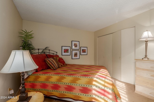 carpeted bedroom featuring a textured ceiling and a closet