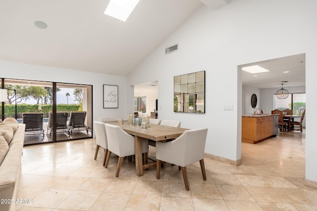 dining space with light tile patterned flooring, high vaulted ceiling, and a skylight