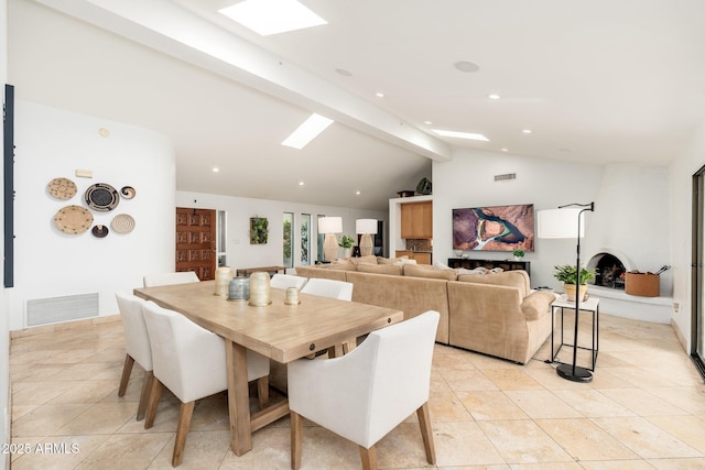 tiled dining area with a fireplace and lofted ceiling with beams