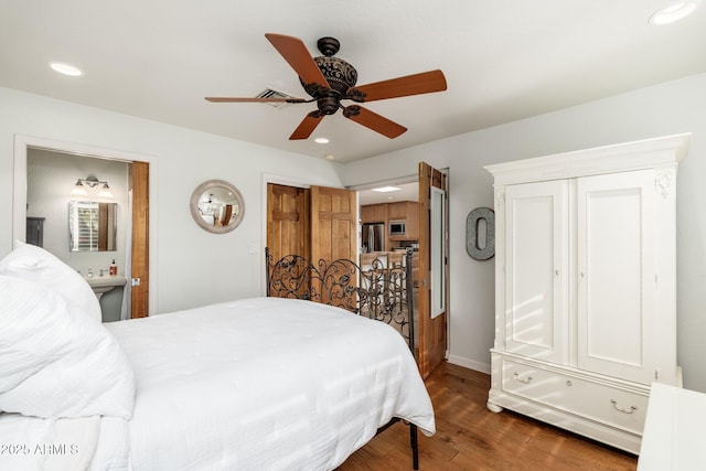 bedroom featuring dark hardwood / wood-style flooring, ensuite bath, and ceiling fan