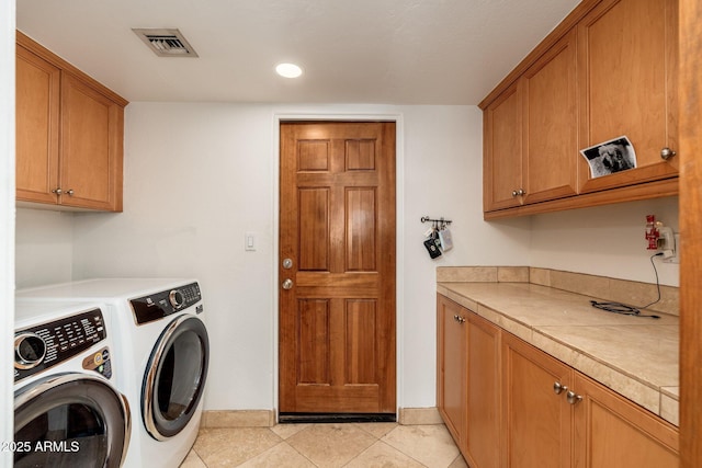 washroom featuring separate washer and dryer, light tile patterned floors, and cabinets