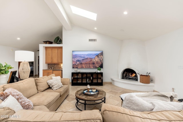 living room featuring a fireplace, beam ceiling, a skylight, and high vaulted ceiling