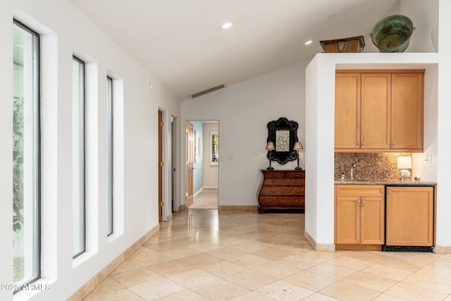 hall with light tile patterned flooring, sink, and vaulted ceiling