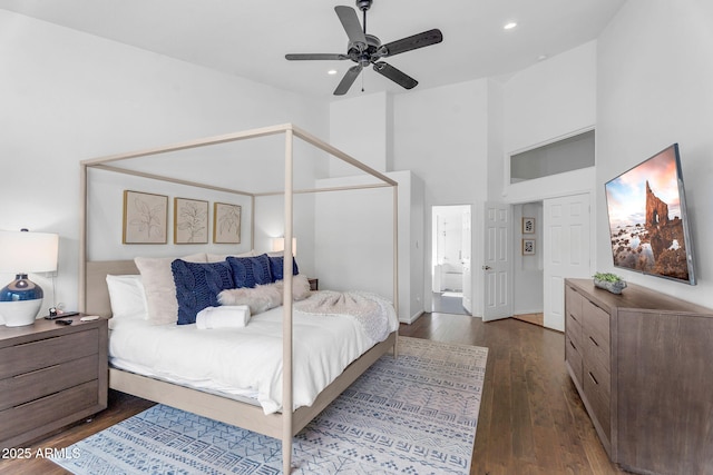 bedroom with connected bathroom, high vaulted ceiling, dark wood finished floors, recessed lighting, and baseboards