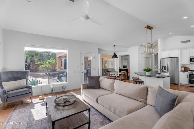living room featuring recessed lighting, ceiling fan, visible vents, and lofted ceiling