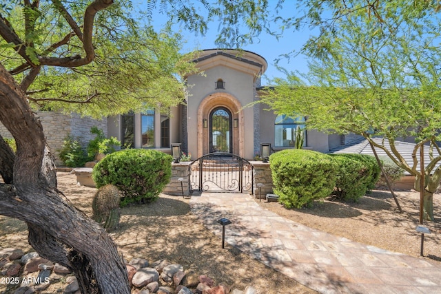doorway to property with stucco siding and a gate