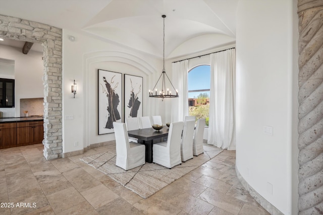 dining room with a notable chandelier, stone tile floors, and lofted ceiling