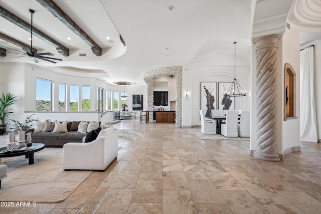 living room featuring decorative columns, stone tile flooring, recessed lighting, and ceiling fan with notable chandelier