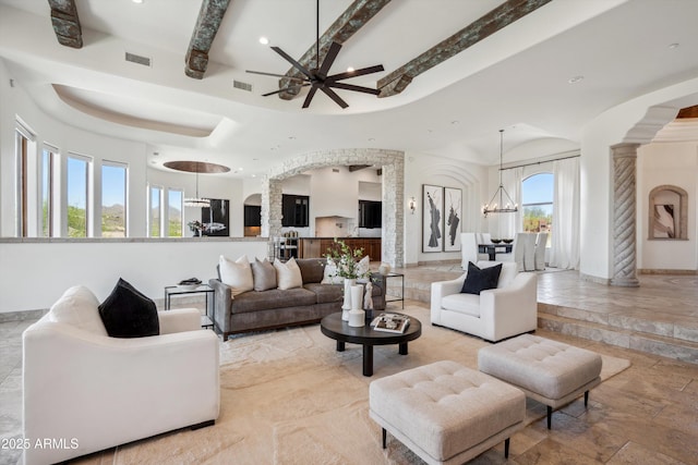 living room featuring beamed ceiling, visible vents, arched walkways, recessed lighting, and ceiling fan with notable chandelier