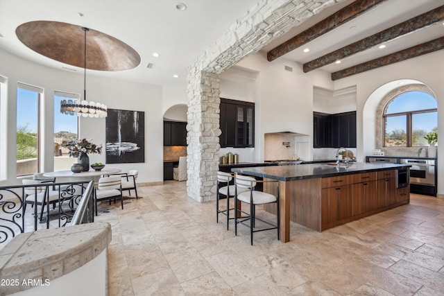 kitchen featuring dark countertops, arched walkways, oven, and a healthy amount of sunlight