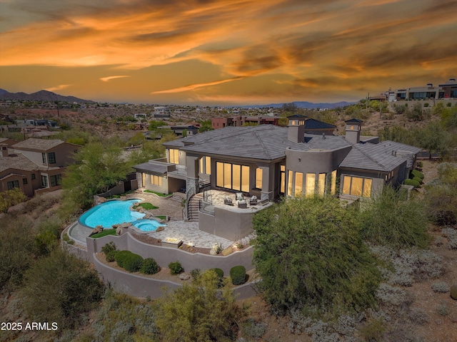 back of property at dusk featuring a chimney, a mountain view, a fenced backyard, and stucco siding