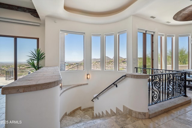 stairway with stone tile flooring, plenty of natural light, a wall unit AC, and visible vents