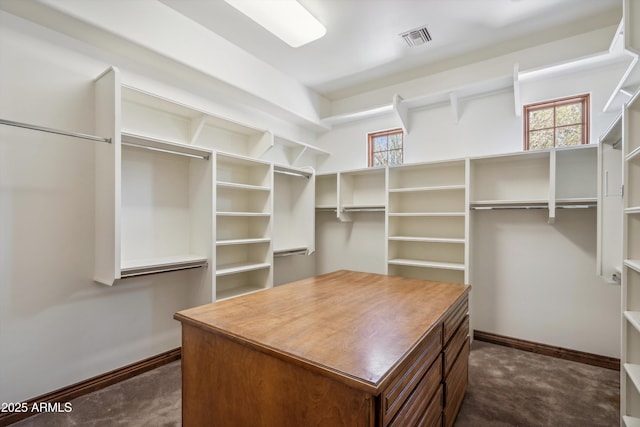 spacious closet featuring visible vents and dark colored carpet