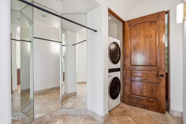 clothes washing area featuring stacked washer and dryer and laundry area
