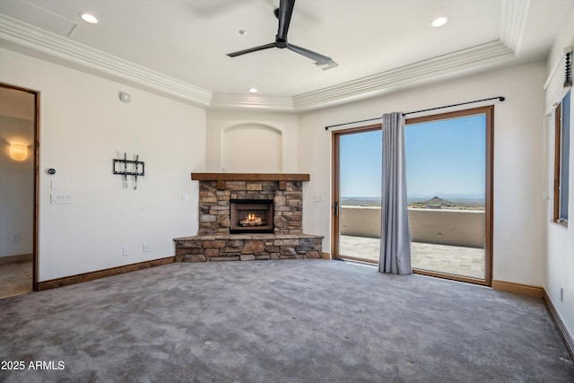 unfurnished living room with carpet floors, ornamental molding, ceiling fan, a fireplace, and baseboards