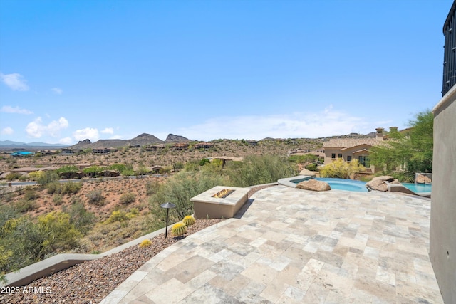 view of patio featuring a mountain view, an outdoor fire pit, an in ground hot tub, and an outdoor pool