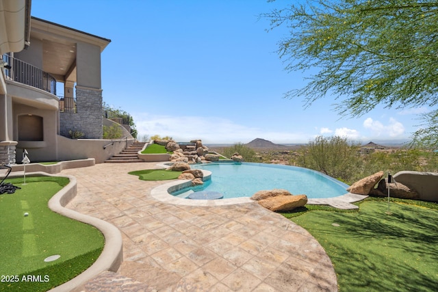 view of pool featuring stairway, an infinity pool, and a patio area