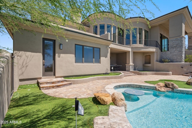 rear view of property with a patio area, stucco siding, a balcony, and an outdoor pool
