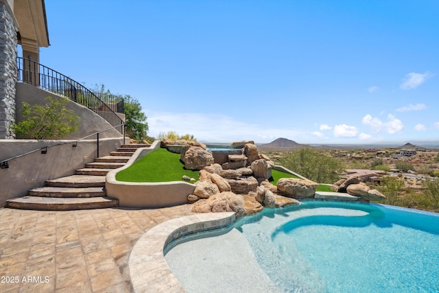 pool featuring a patio, a mountain view, and stairs