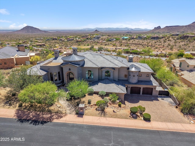 view of front facade with a garage, a mountain view, stucco siding, and driveway