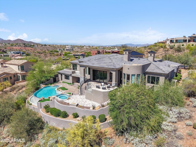back of property with a chimney, a fenced backyard, stucco siding, a pool with connected hot tub, and a patio area