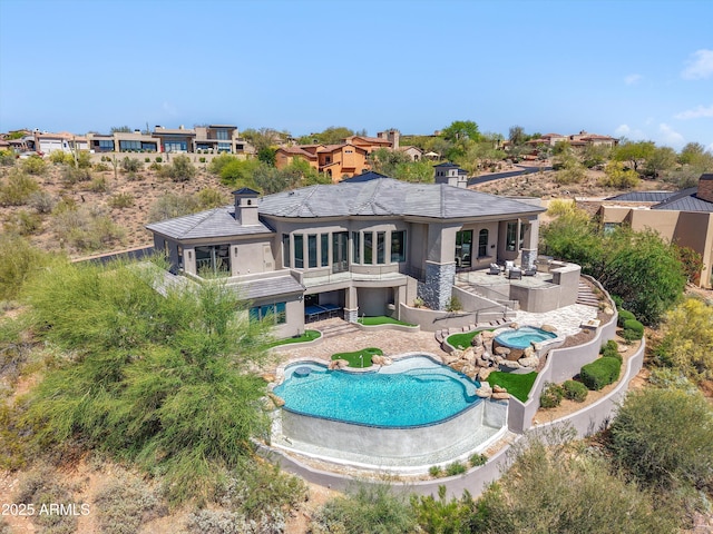 rear view of house featuring a fenced backyard, stucco siding, an in ground hot tub, and an outdoor pool
