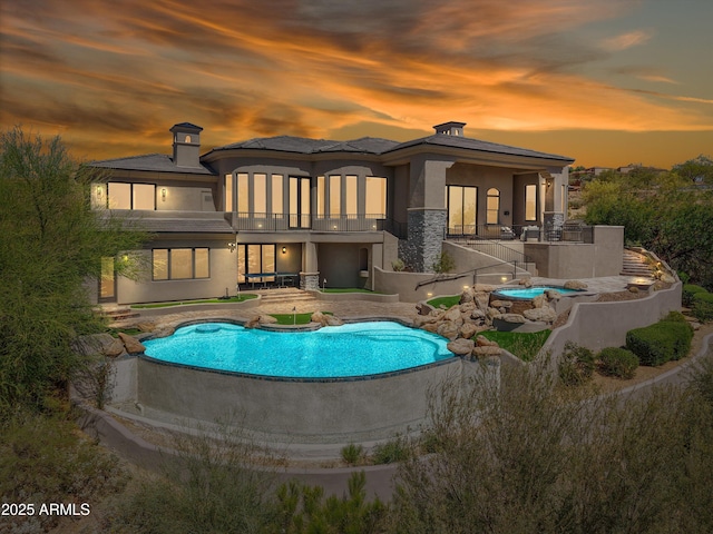 rear view of house featuring a chimney, stucco siding, a patio, a balcony, and an outdoor pool