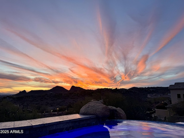 pool at dusk with an infinity pool and a mountain view