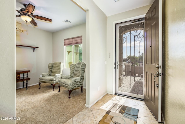 living area featuring tile patterned floors, visible vents, a ceiling fan, and vaulted ceiling