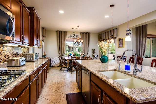 kitchen with light tile patterned flooring, sink, stainless steel appliances, a notable chandelier, and decorative light fixtures