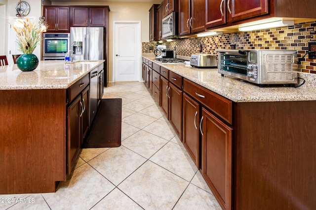 kitchen featuring appliances with stainless steel finishes, light tile patterned floors, light stone countertops, and backsplash