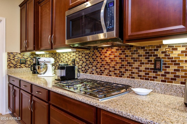 kitchen featuring pendant lighting, decorative backsplash, stainless steel appliances, a kitchen island, and a notable chandelier