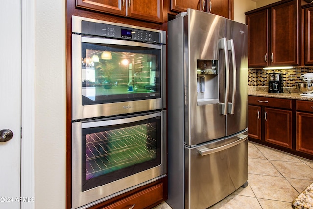 kitchen featuring light tile patterned floors, light stone countertops, stainless steel appliances, and decorative backsplash