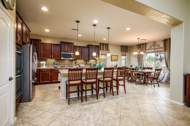 kitchen featuring pendant lighting, tasteful backsplash, a chandelier, stainless steel appliances, and a center island