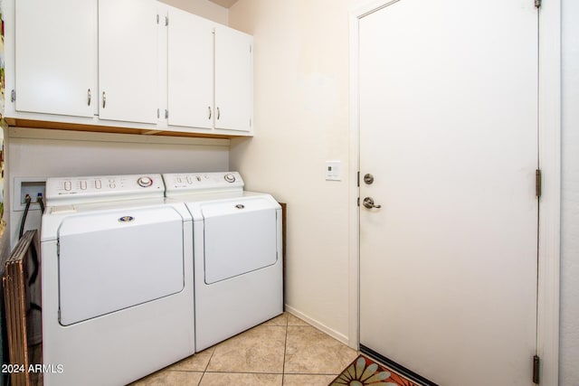 laundry room featuring light tile patterned floors, separate washer and dryer, cabinet space, and baseboards