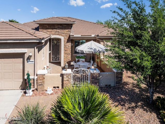 exterior space featuring a tile roof, a garage, a fenced front yard, a gate, and stone siding