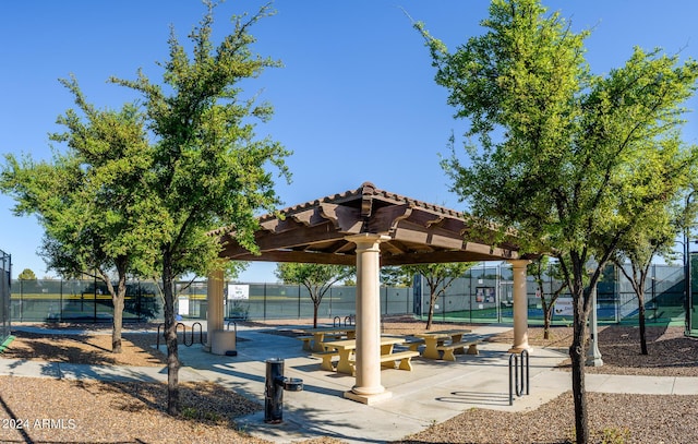 view of community featuring fence, a gazebo, and a tennis court