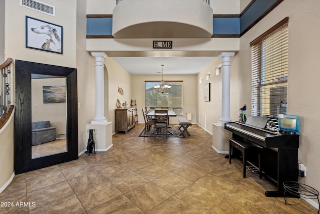 foyer featuring tile patterned floors, a notable chandelier, a healthy amount of sunlight, and a high ceiling