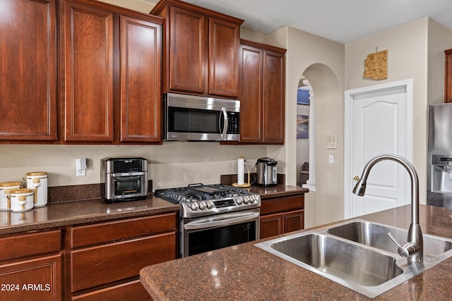 kitchen with dark stone countertops, sink, and stainless steel appliances