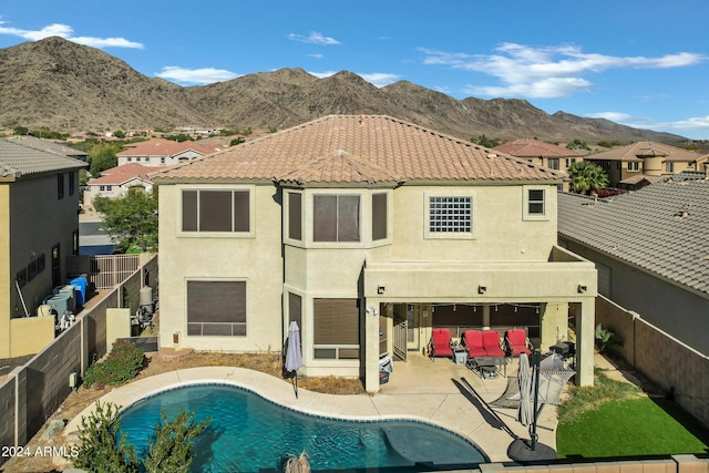 rear view of property with a mountain view, a patio area, and a fenced in pool