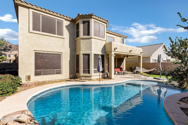 rear view of property with a balcony, a fenced in pool, and a patio