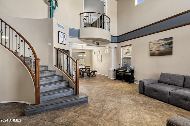 interior space with a high ceiling, an inviting chandelier, ornate columns, and a healthy amount of sunlight